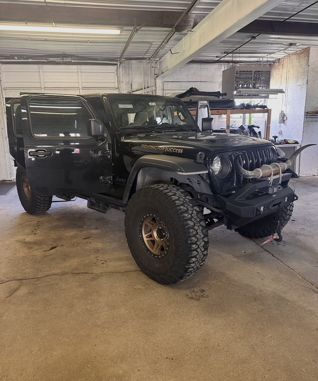 Black and white photograph of a built Jeep Gladiator marked Fighting for Success in the garage